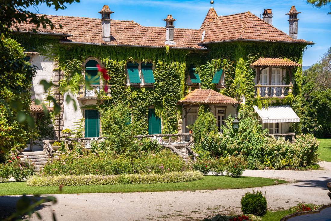 Ivy-covered stone manor house with green shutters and garden in northern Portugal
